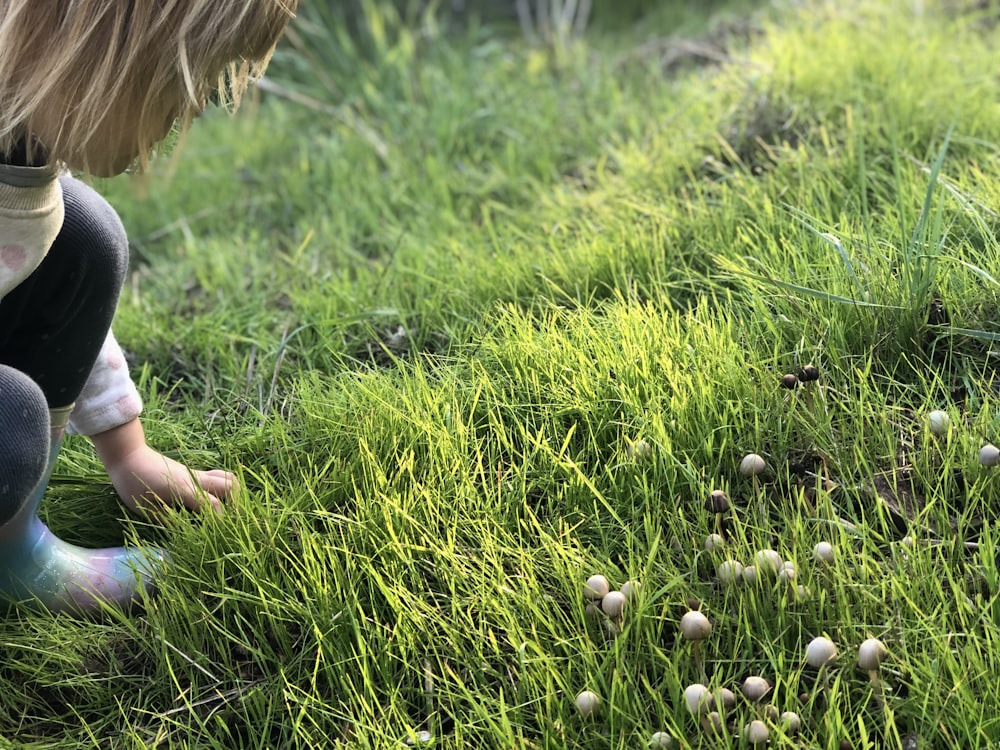 girl in white shirt walking on green grass field during daytime