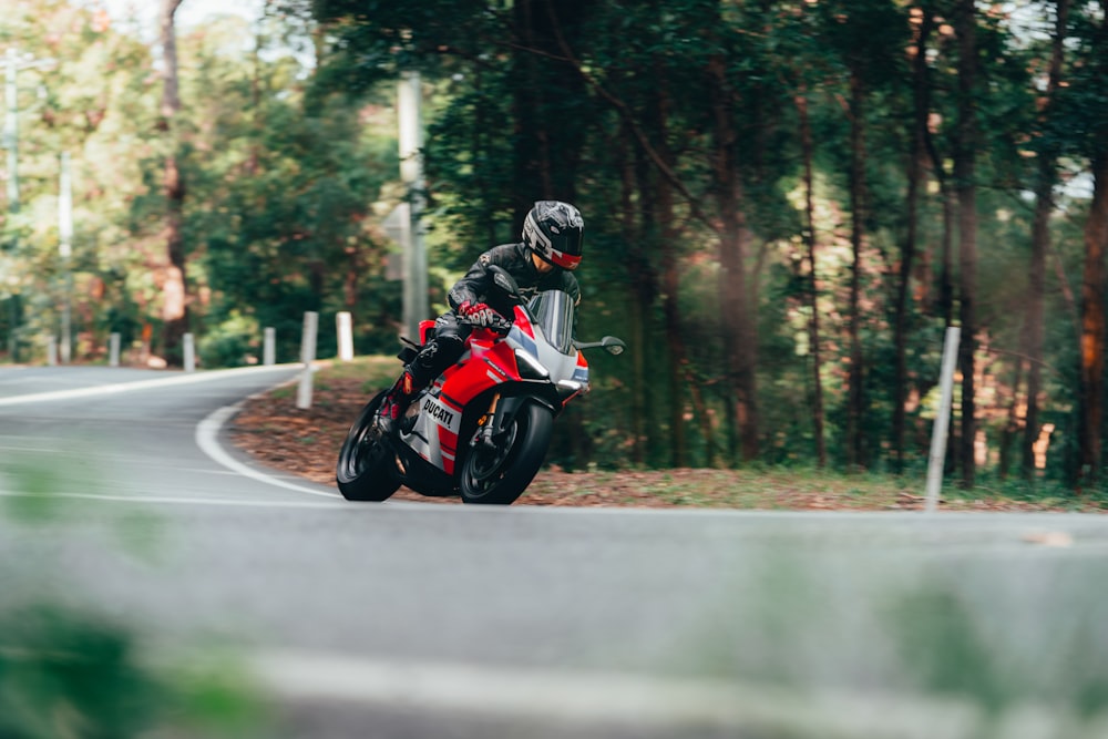 homem no capacete preto que monta a motocicleta na estrada durante o dia