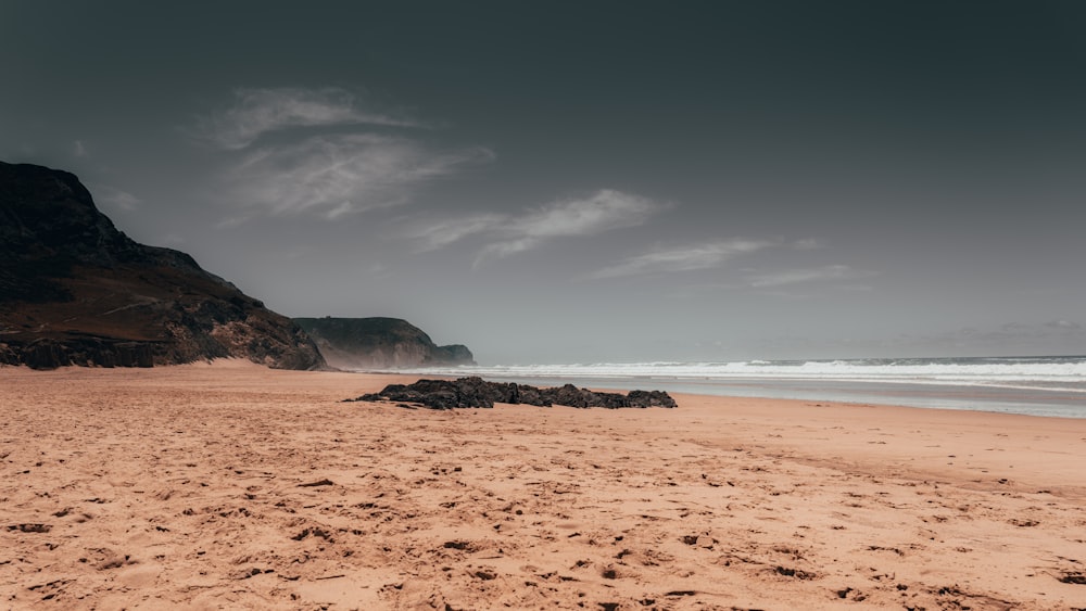 brown sand beach with ocean waves crashing on shore during daytime