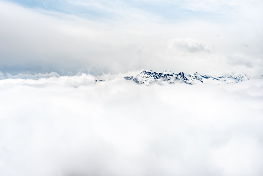 snow covered mountain under white clouds during daytime