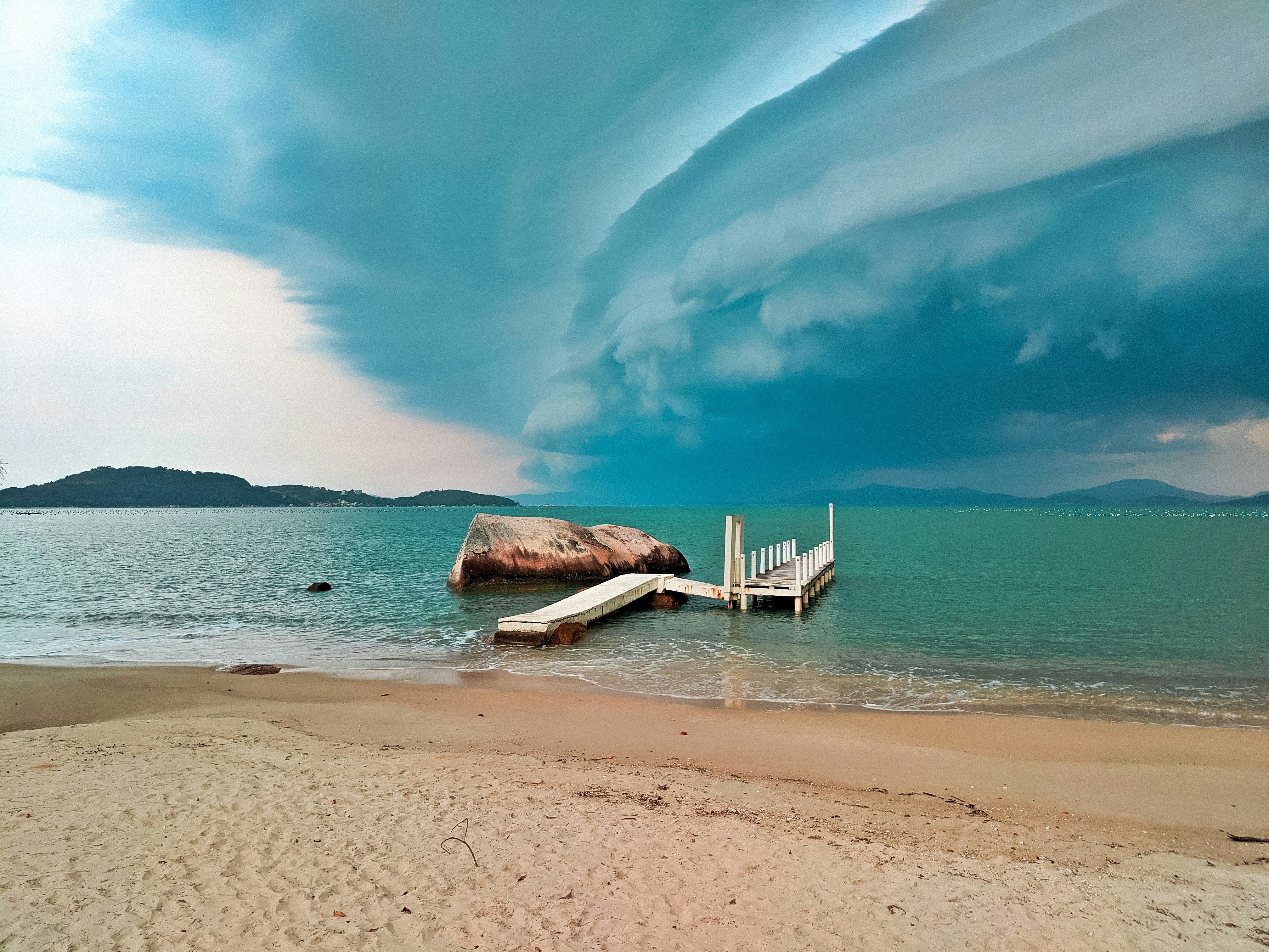cadeira de praia de madeira branca na costa da praia durante o dia
