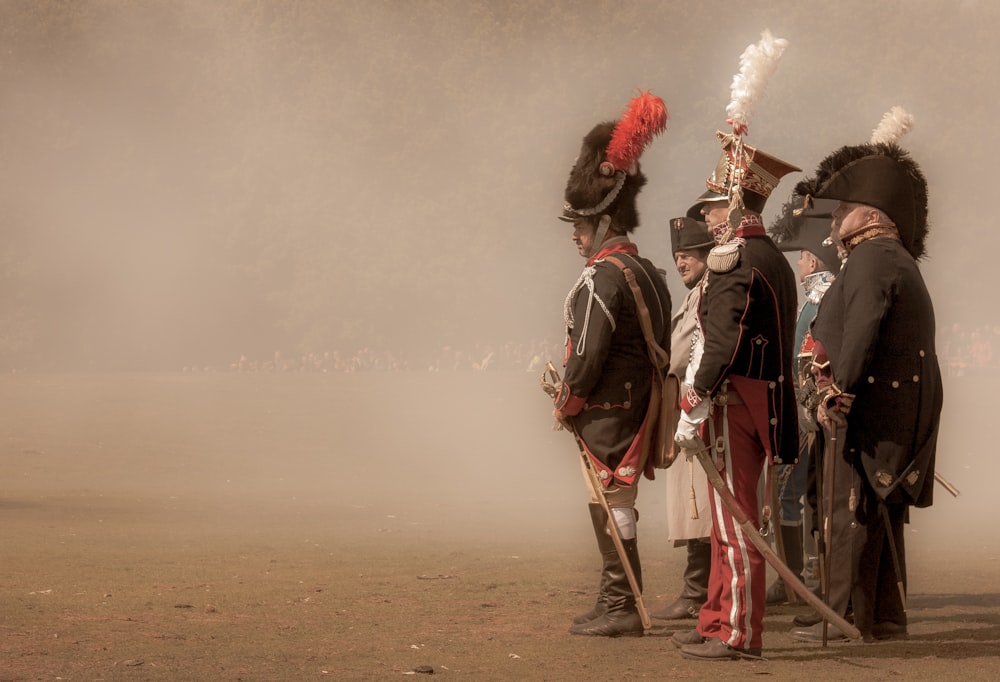 3 men in black and white suit holding red smoke hose