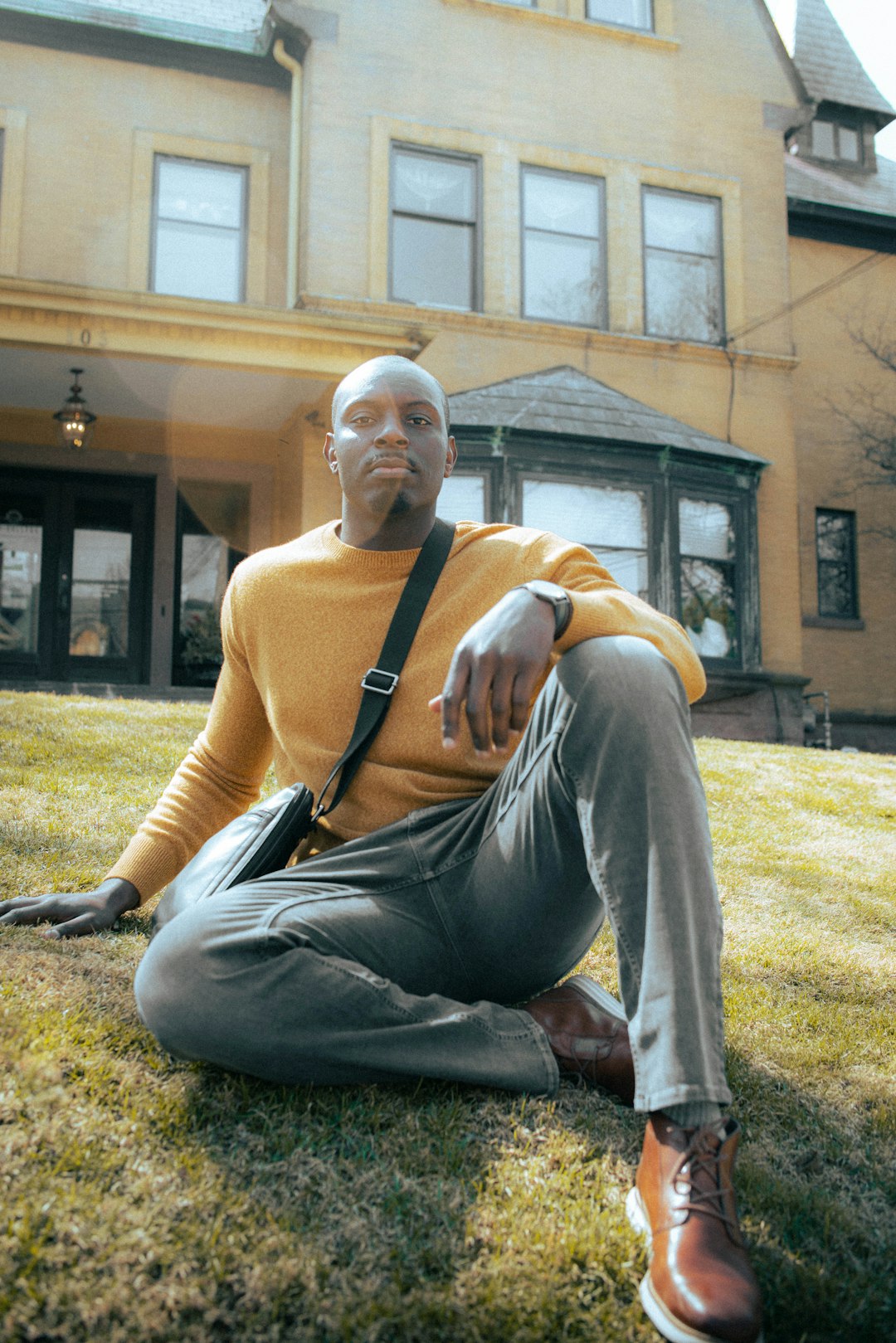 man in brown tank top sitting on green grass field during daytime