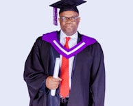 man in black academic dress wearing black academic hat