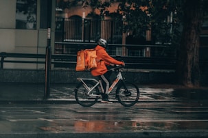 man in orange jacket riding bicycle on street during nighttime