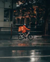 man in orange jacket riding bicycle on street during nighttime