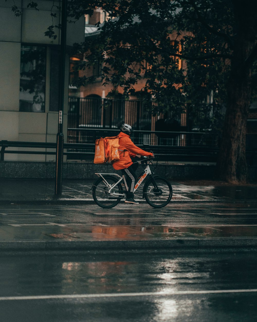 uomo in giacca arancione che va in bicicletta sulla strada durante la notte