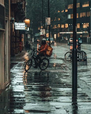 person in black jacket riding bicycle on sidewalk during daytime