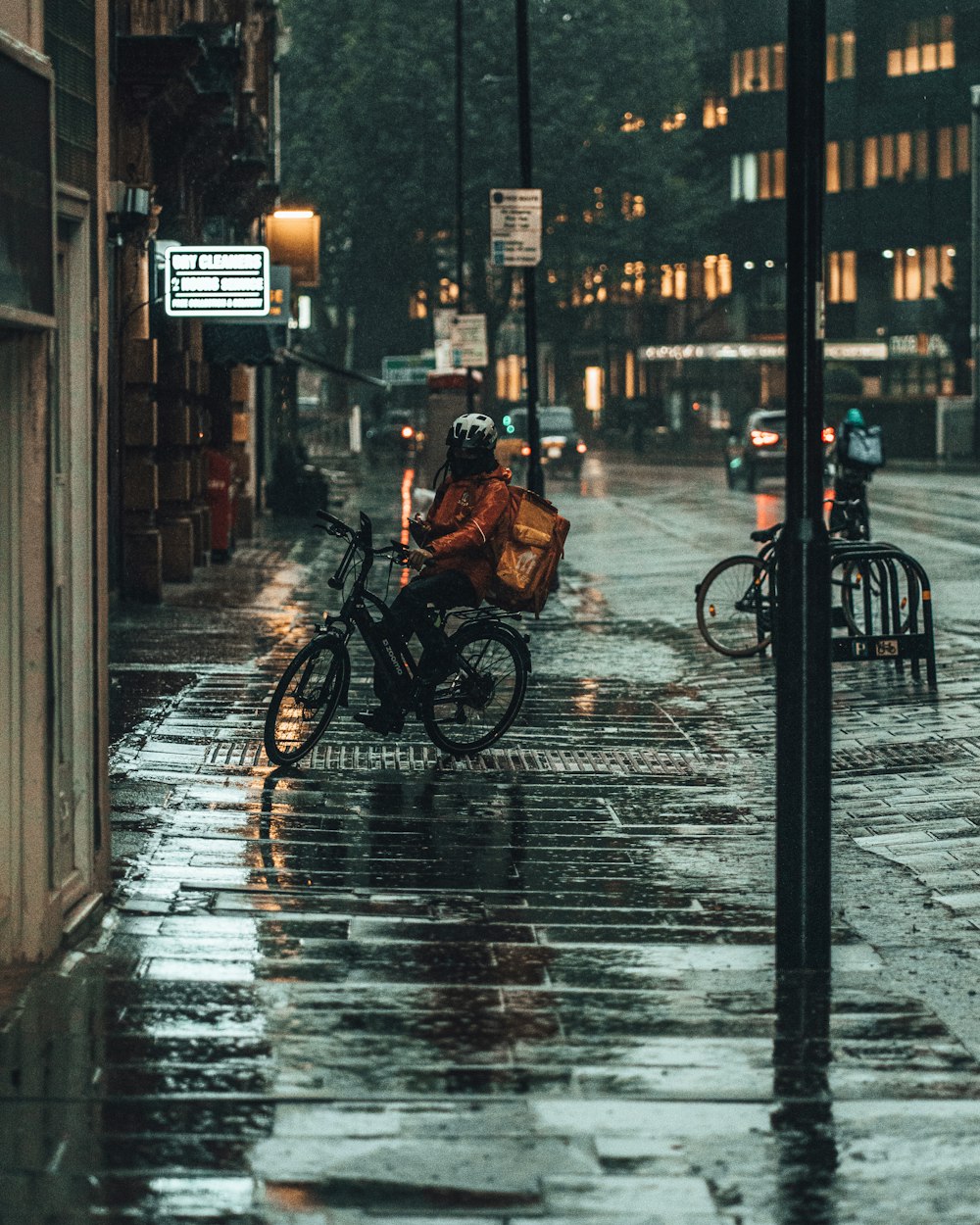 Persona en chaqueta negra montando en bicicleta en la acera durante el día