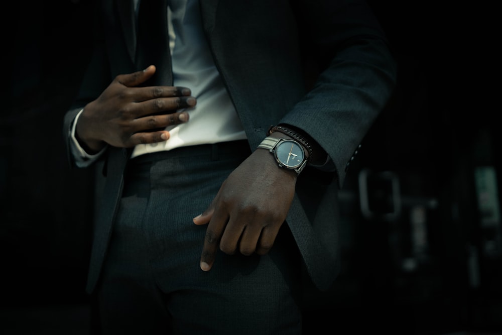 man in black suit jacket and black pants wearing silver round analog watch