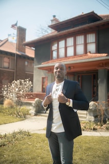 man in black suit standing near brown brick building during daytime