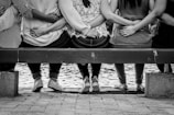 grayscale photo of 3 women sitting on wooden bench