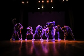 A group of dancers performing a synchronized routine on stage with colorful lighting