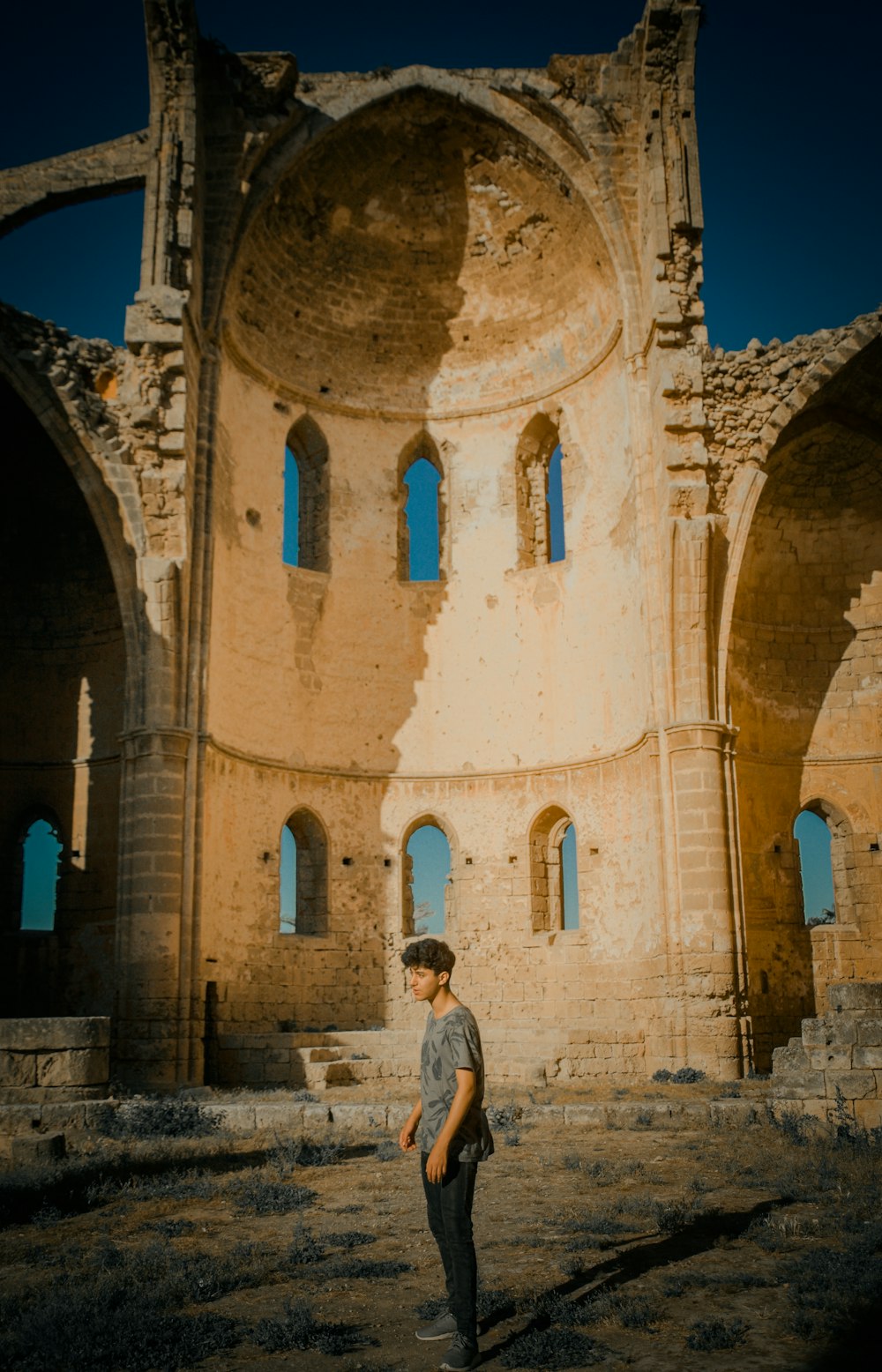 man in white shirt standing in front of brown concrete building during daytime