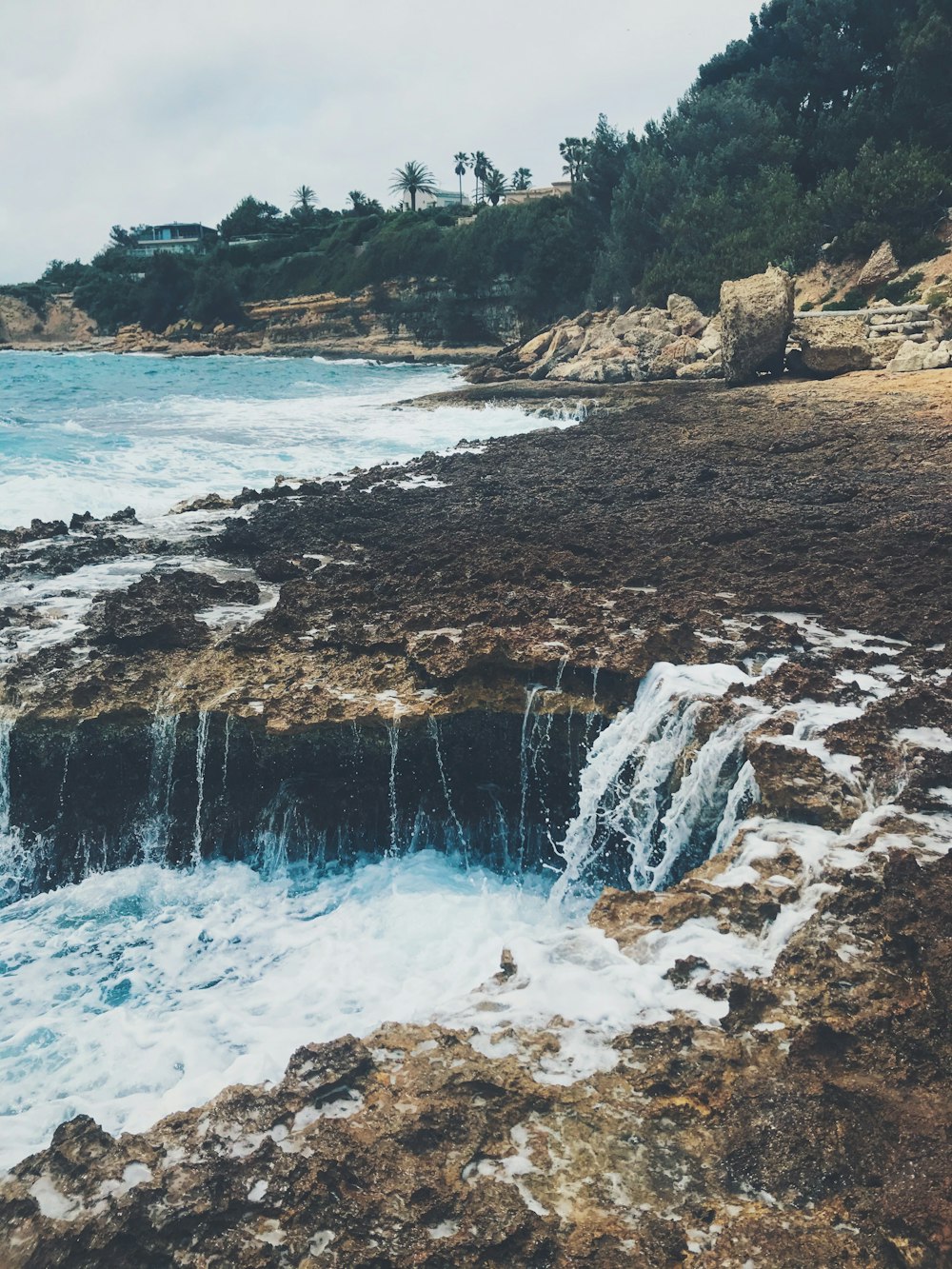 water falls on rocky shore during daytime