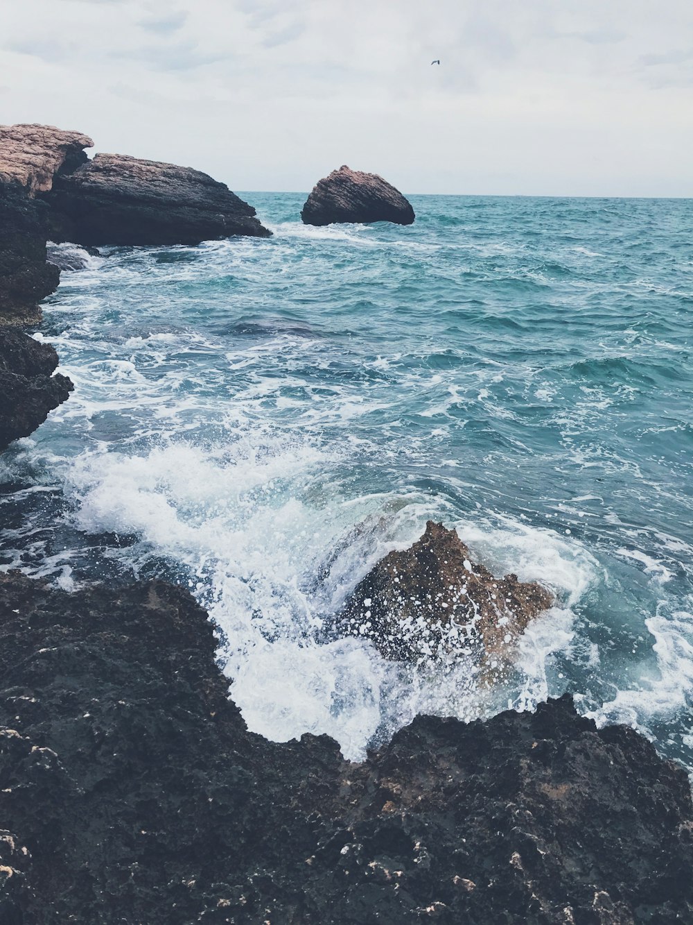 Les vagues de l’océan s’écrasent sur la formation de roche brune pendant la journée