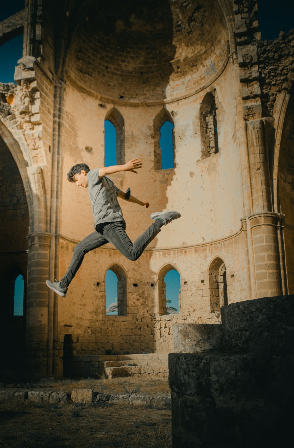 man in white long sleeve shirt and gray pants jumping in mid air