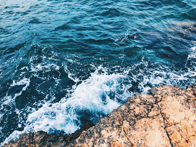 brown rocky shore with water waves during daytime