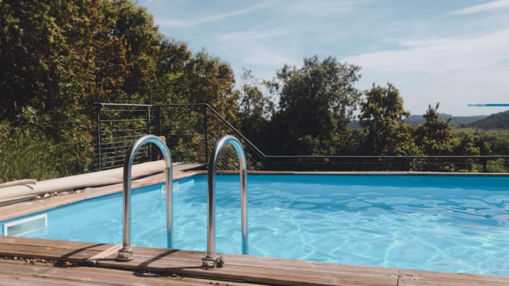 white swimming pool near green trees during daytime