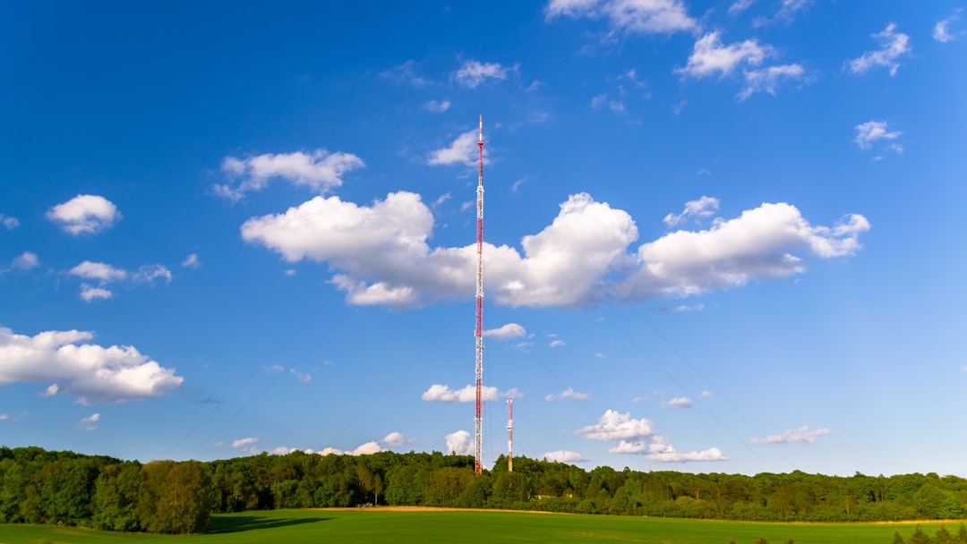white and red flag pole on green grass field under blue and white cloudy sky during