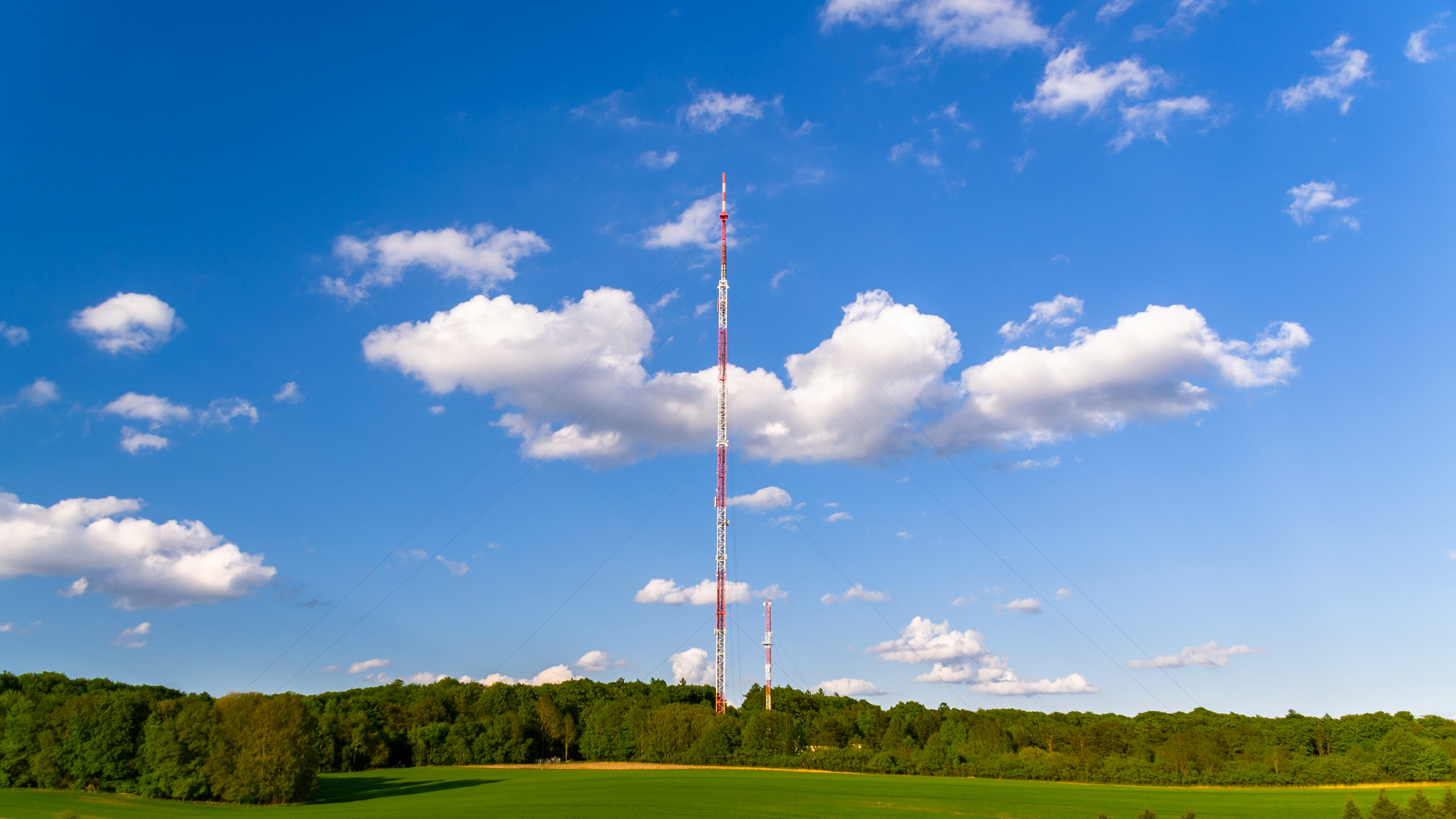 white and red flag pole on green grass field under blue and white cloudy sky during