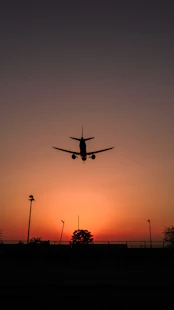 silhouette of airplane flying during sunset