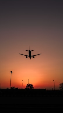 silhouette of airplane flying during sunset