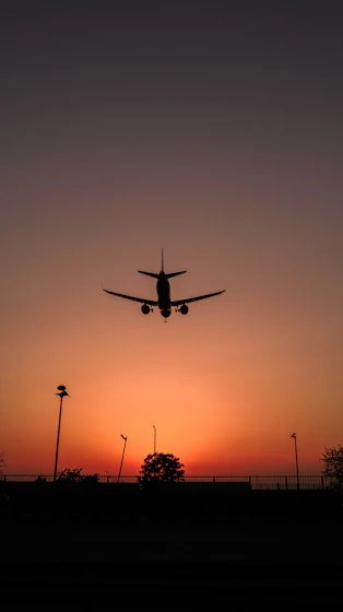 silhouette of airplane flying during sunset