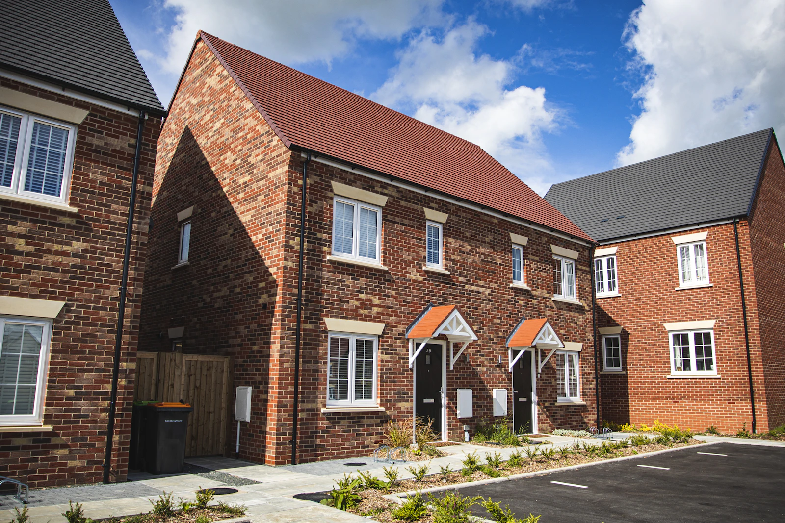 A brown brick British house under a blue sky