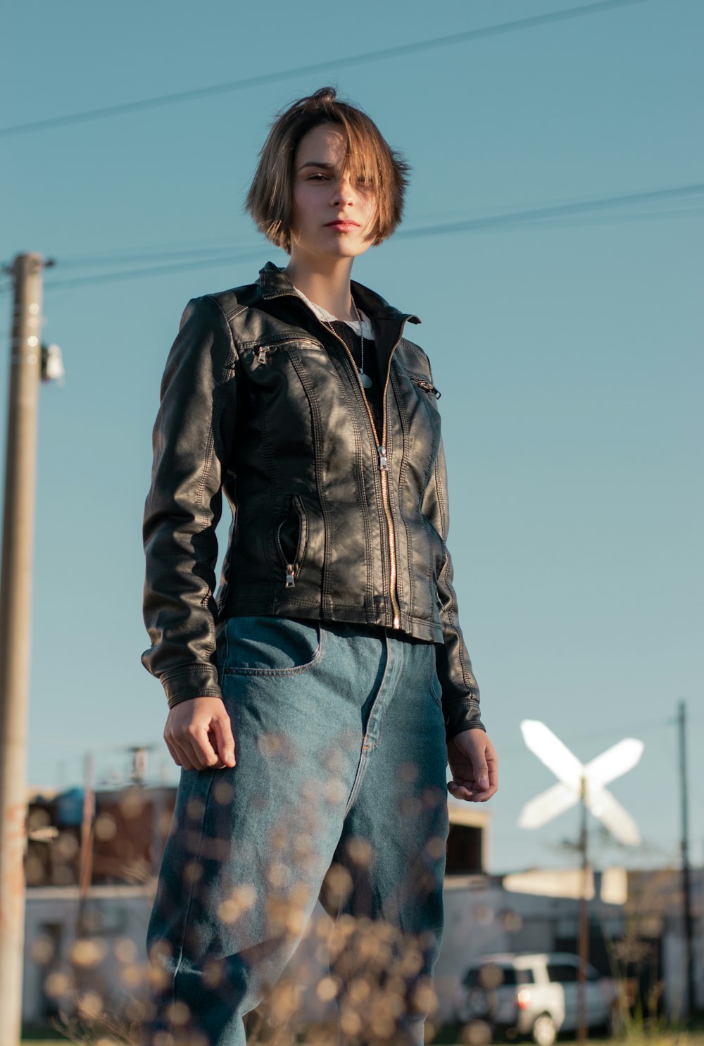 woman in black leather jacket and blue denim jeans standing during daytime