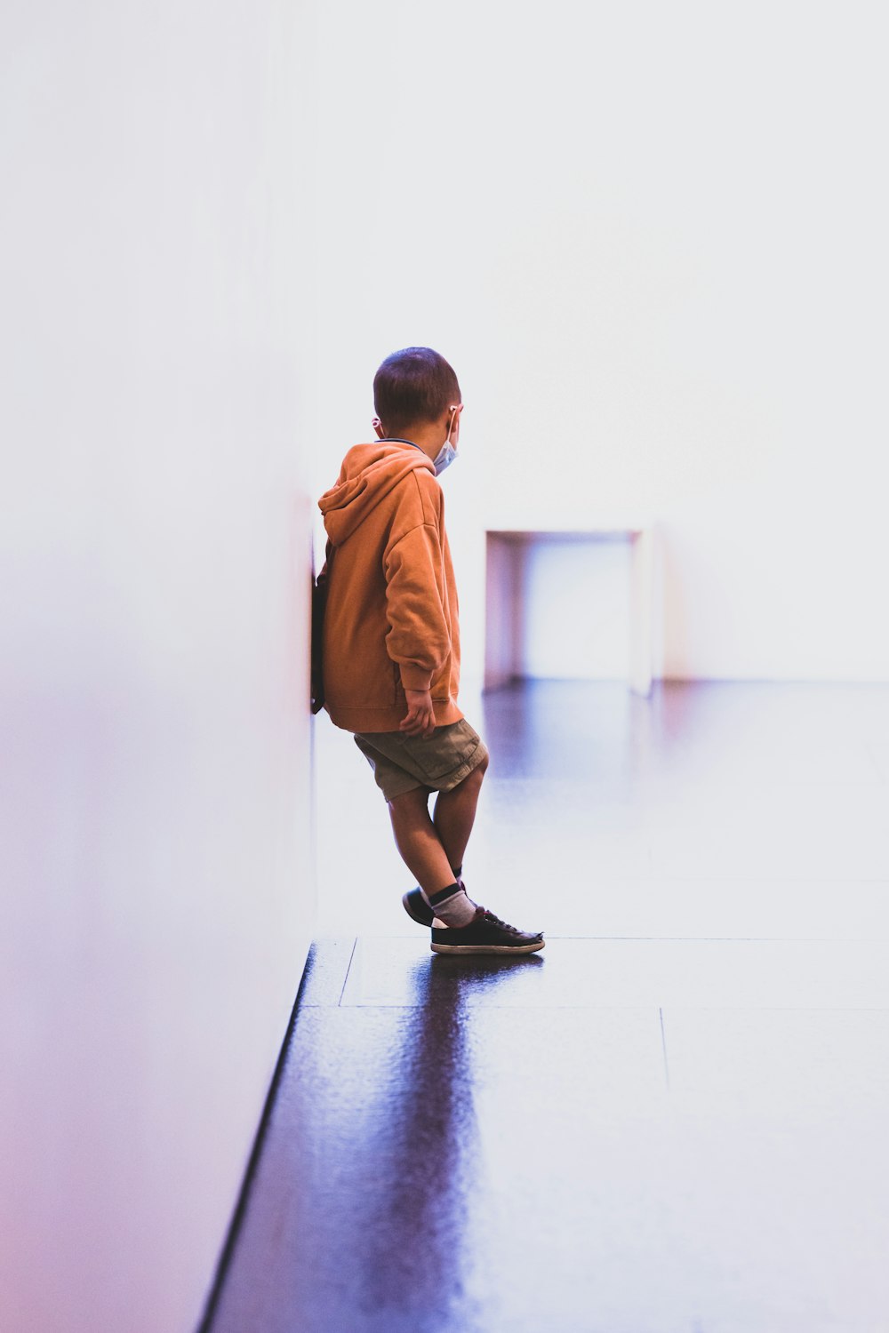 boy in brown long sleeve shirt and brown shorts standing on black floor