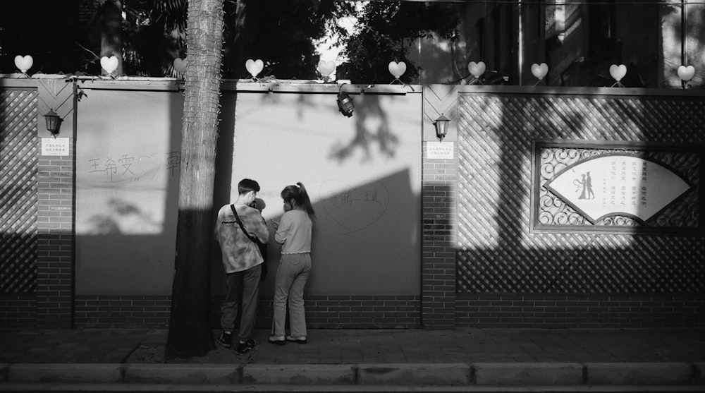 grayscale photo of man and woman walking on sidewalk