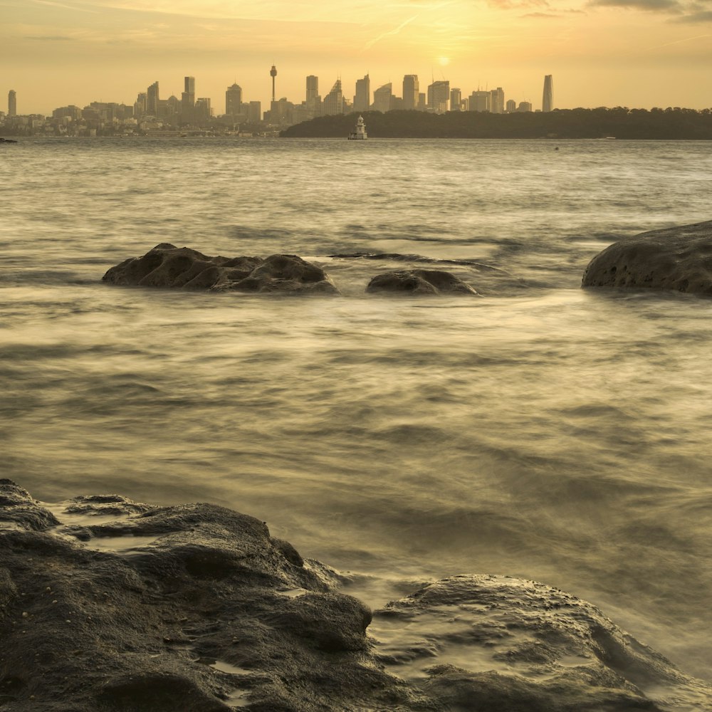 silhouette of rocks on sea during sunset