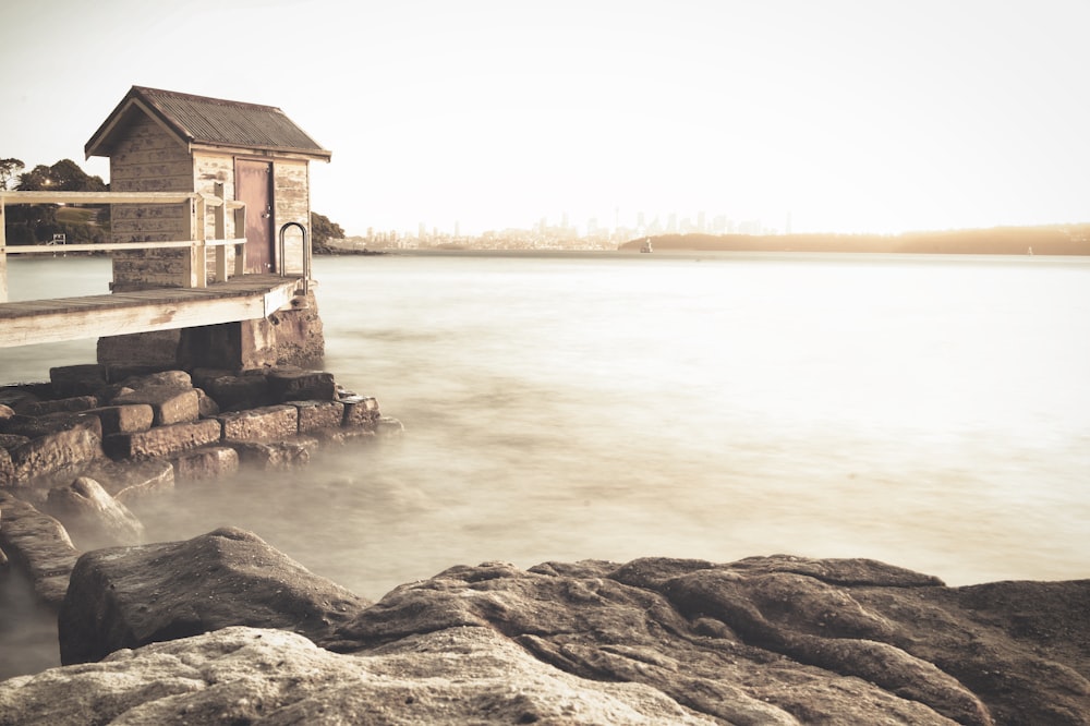 brown wooden house on brown rock near body of water during daytime