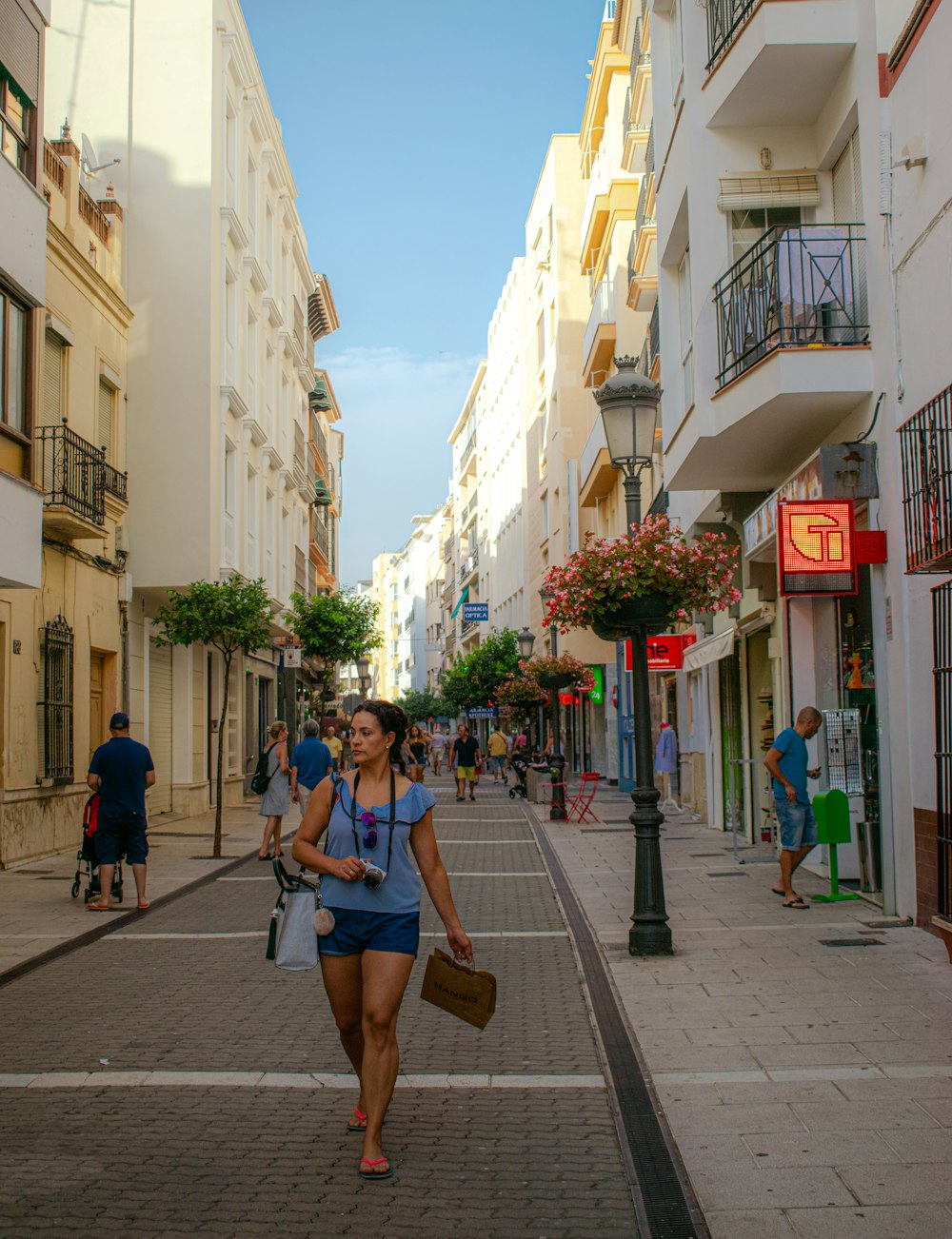 woman in blue denim shorts walking on sidewalk during daytime