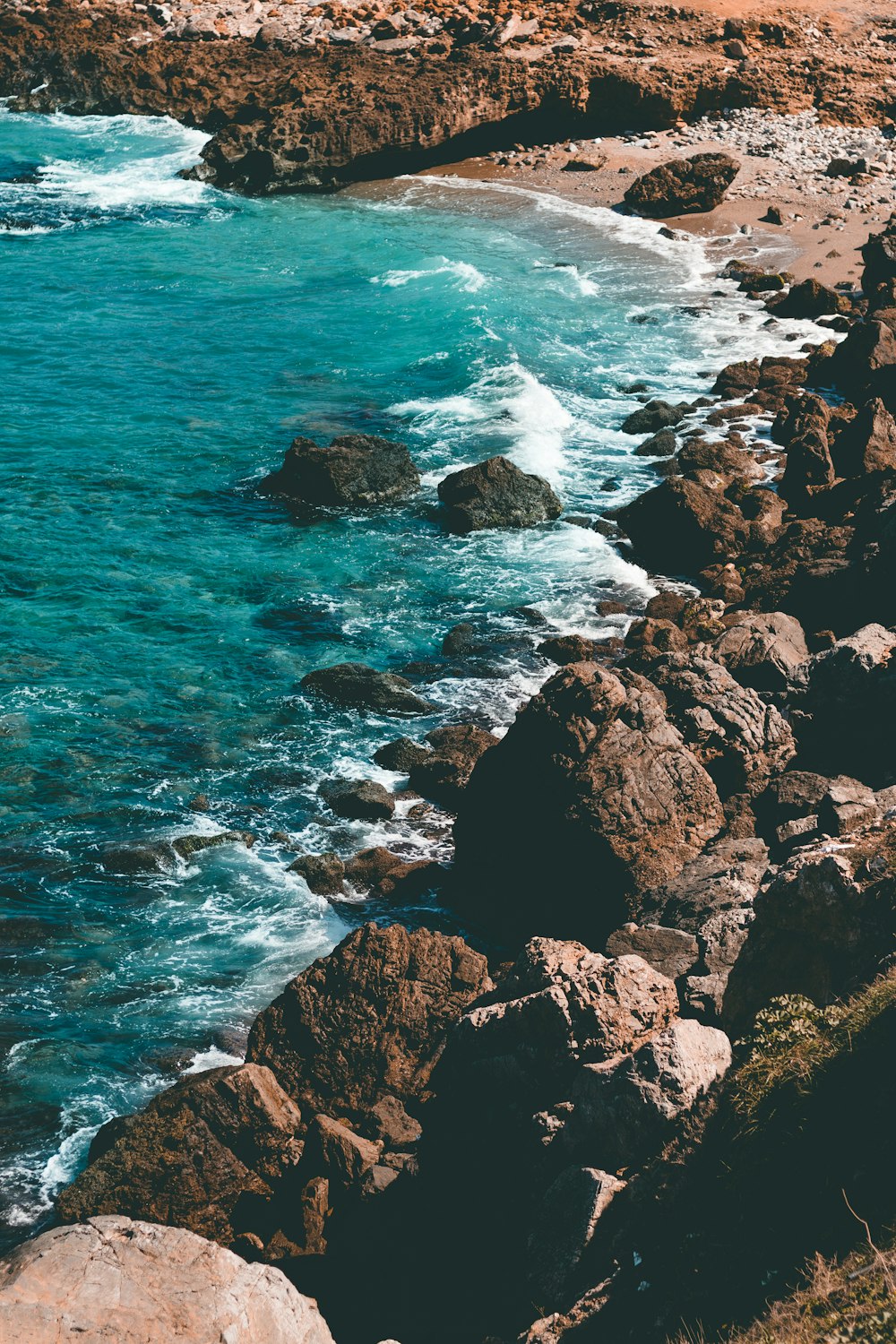 日中に海の波が岩に打ち寄せる茶色の岩だらけの海岸