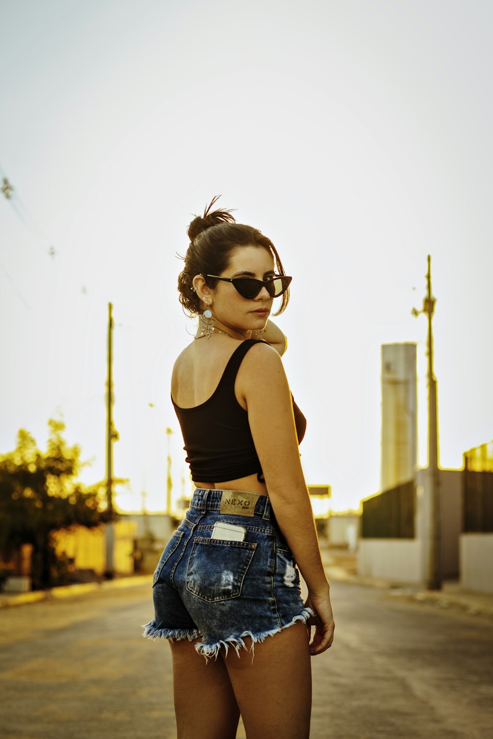 woman in black tank top and blue denim shorts wearing black sunglasses