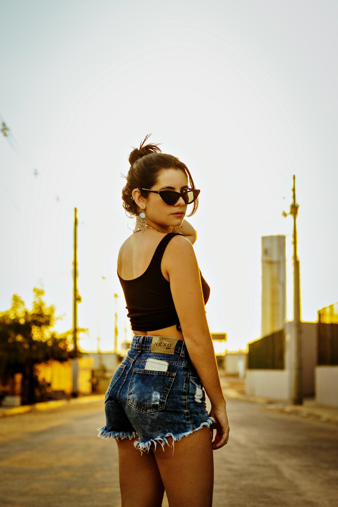 woman in black tank top and blue denim shorts wearing black sunglasses