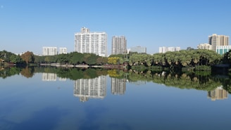 Elegant high-rise buildings of Ganga County reflecting in a serene water body under a clear blue sky.