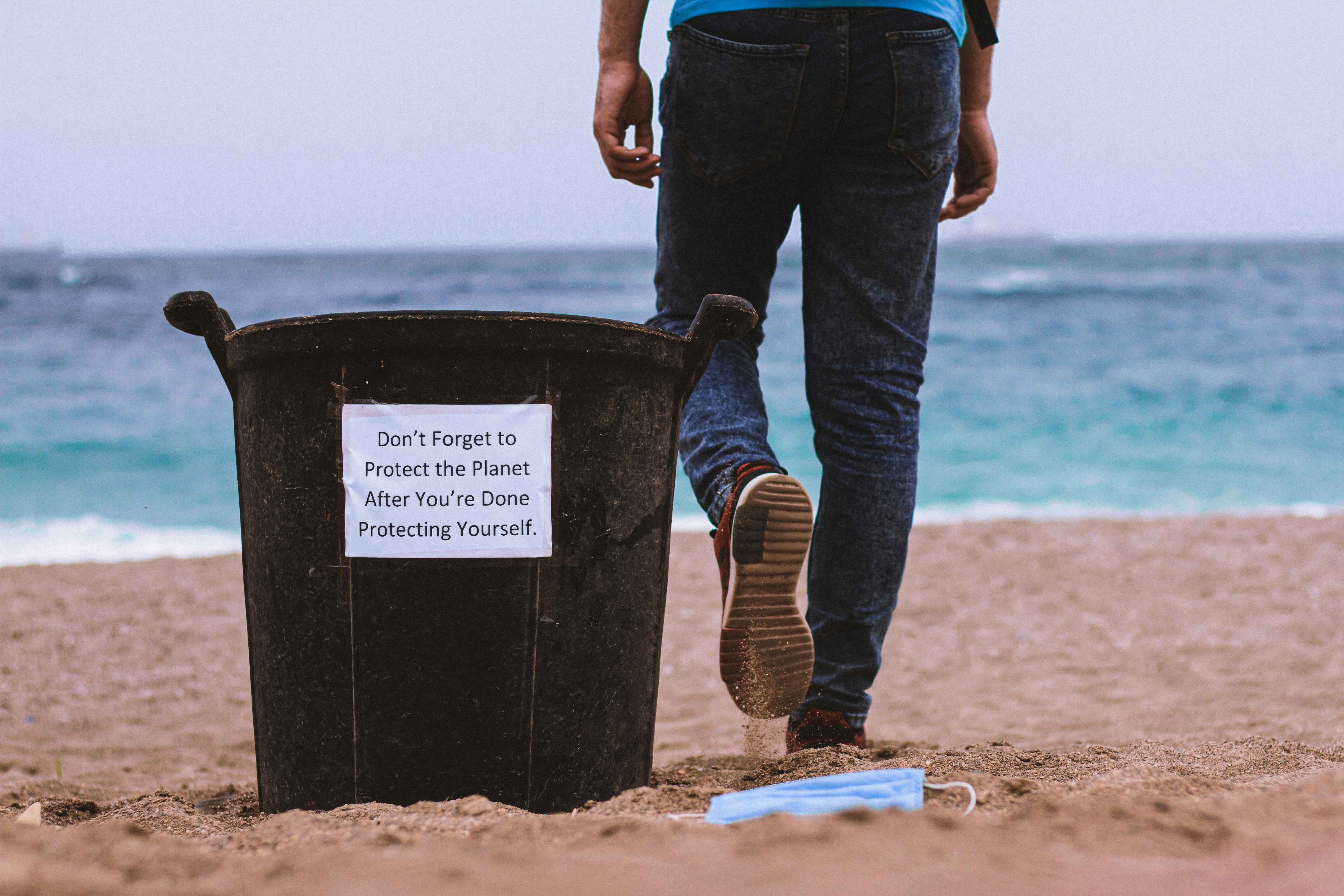 person in blue denim jeans and brown boots standing on beach shore during daytime
