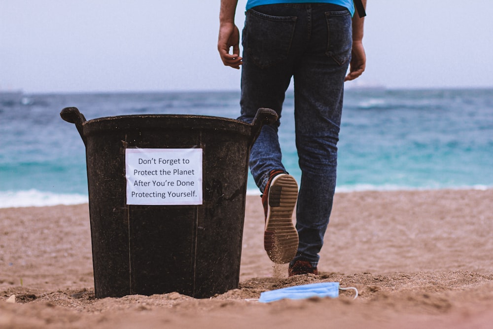 person in blue denim jeans and brown boots standing on beach shore during daytime