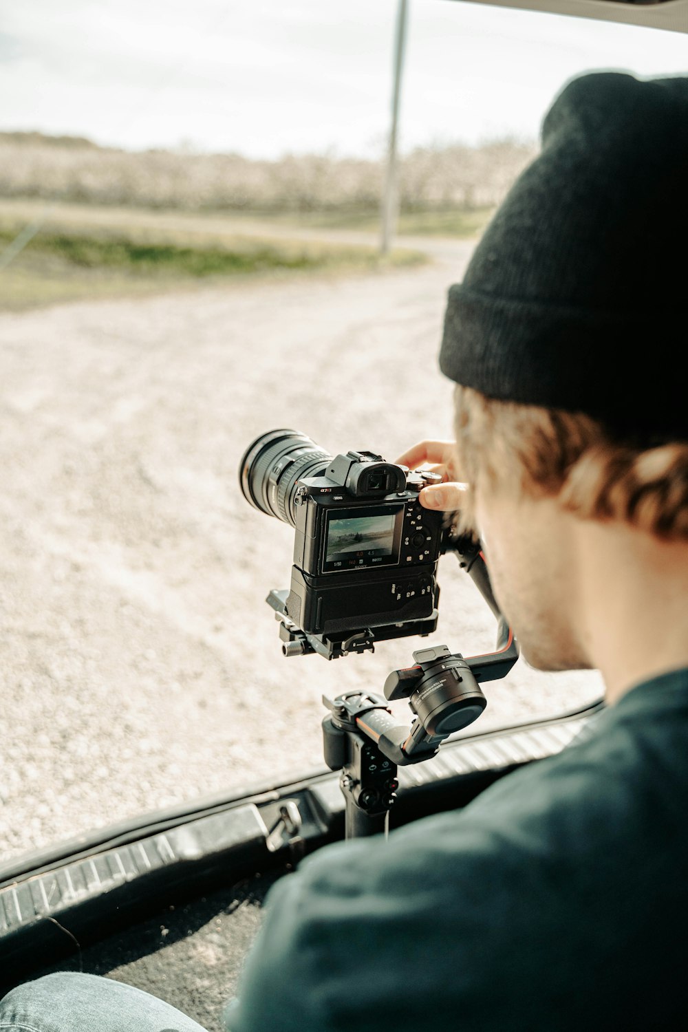 man in black knit cap holding black dslr camera