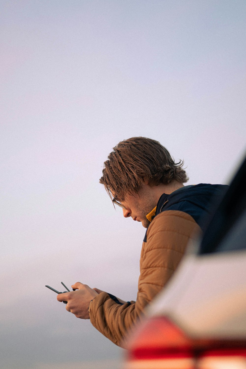 man in brown and blue long sleeve shirt holding smartphone