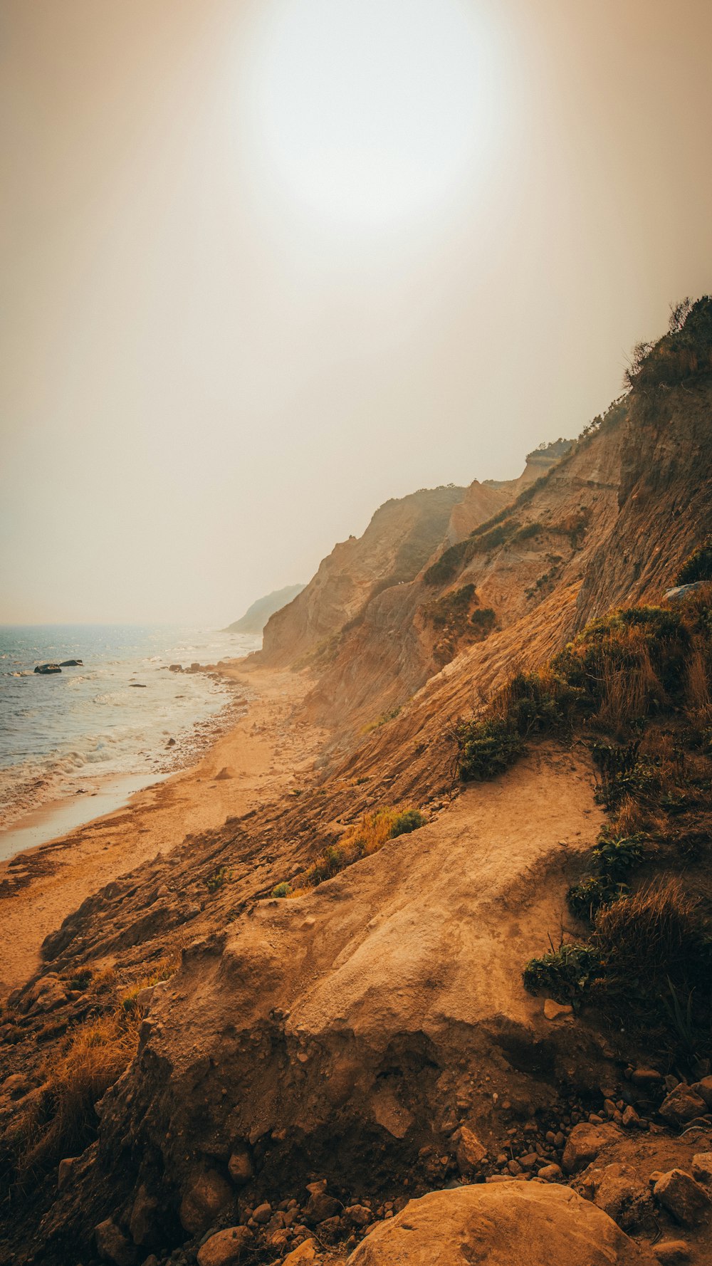 brown rocky mountain beside sea during daytime