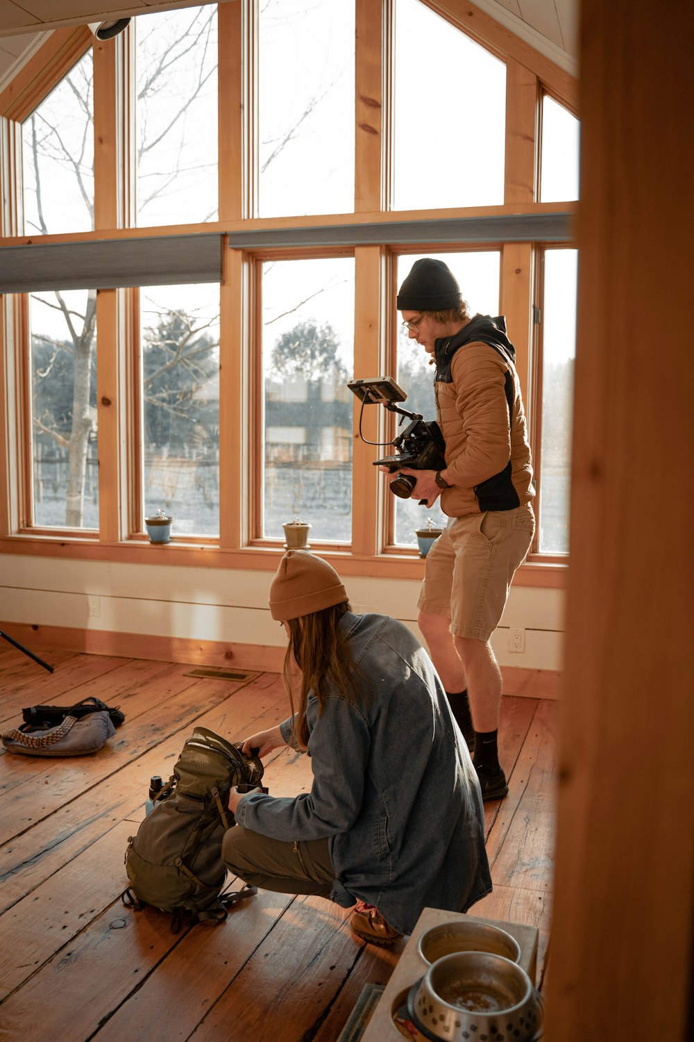 hombre con sudadera con capucha gris tomando foto de una ventana de vidrio con marco de madera marrón