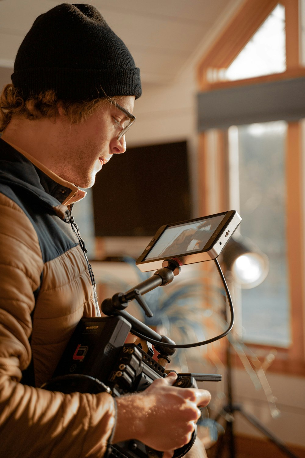 man in black knit cap and brown jacket using black laptop computer