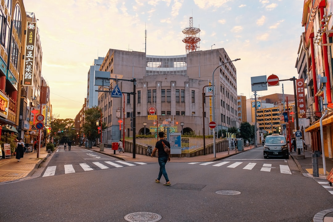 man in black jacket and blue denim jeans walking on pedestrian lane during daytime