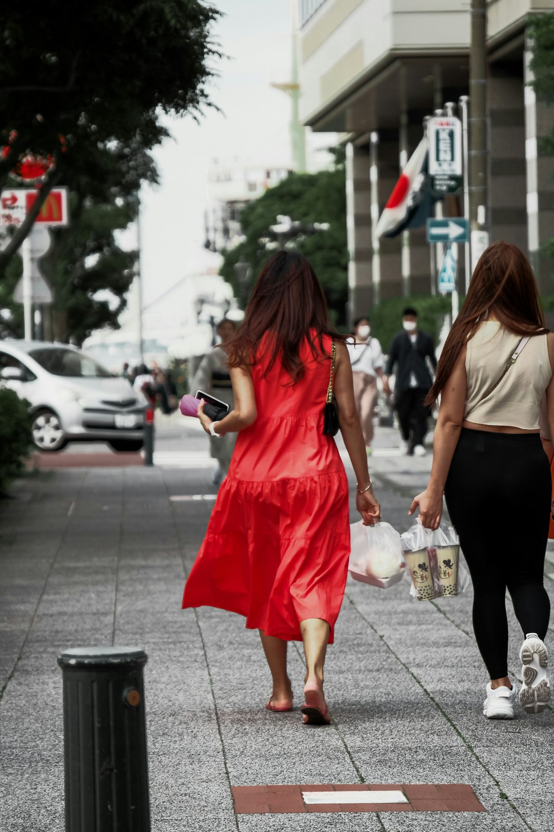 woman in red sleeveless dress standing on sidewalk during daytime