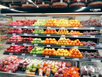 Fresh fruits and vegetables neatly arranged in colorful baskets in a supermarket aisle.