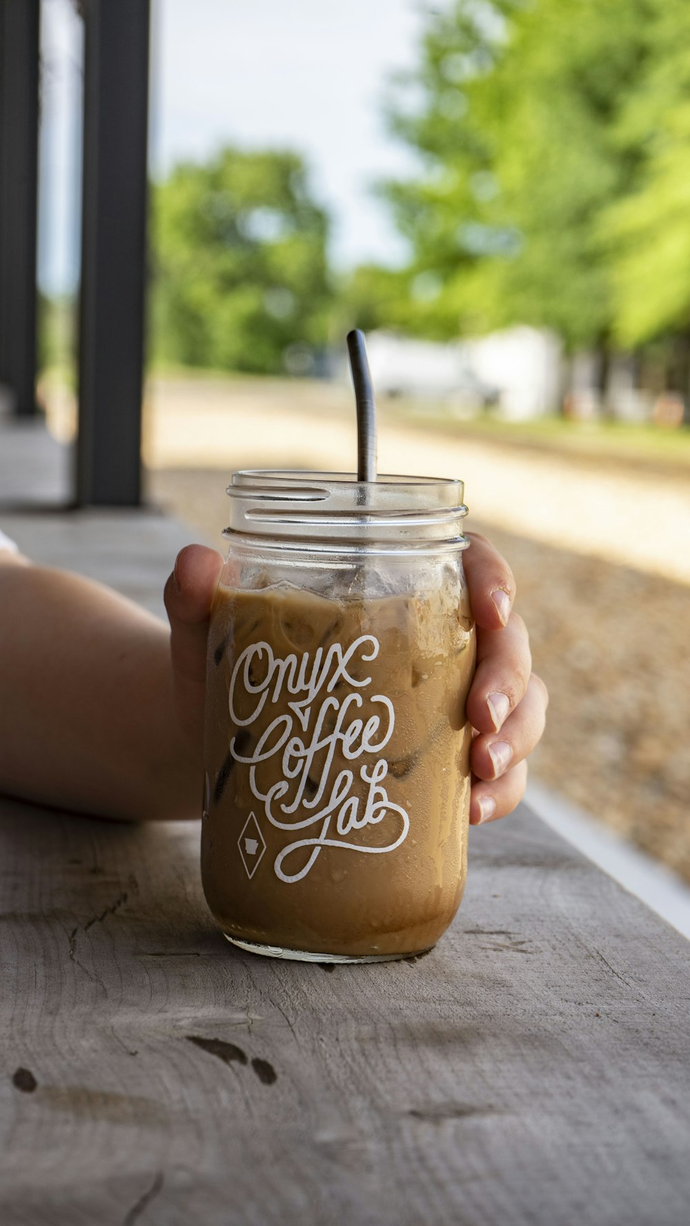 person holding clear glass jar with black straw